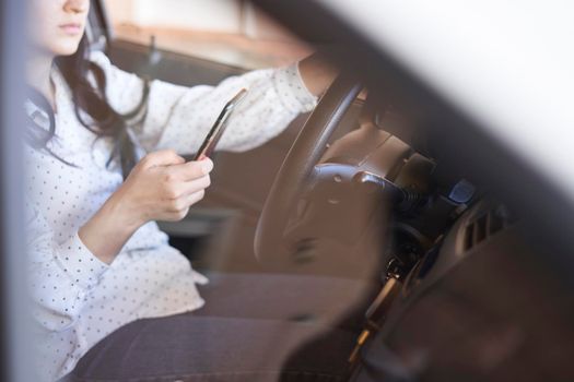 Young multiracial woman texting and driving car. Woman using cellphone while driving car. Female using smartphone while travelling by car. Driving while holding cell phone