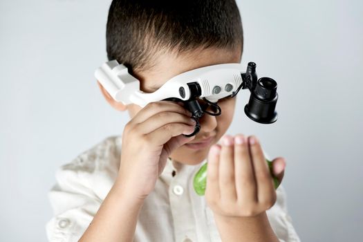 A boy in head magnifying glasses headset learning Incredible chemistry of slimes. Tactile play or sensory play for older kids