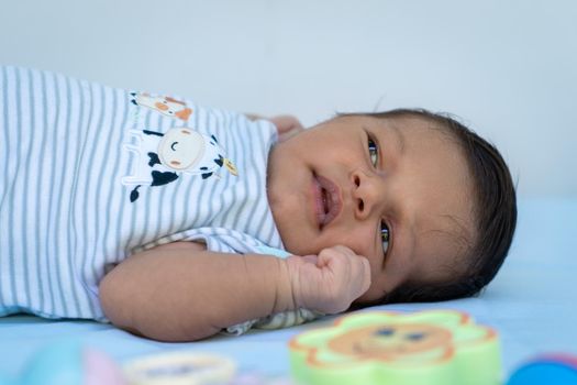 Close up photo of an infant with his eyes open lying on a blue cloth