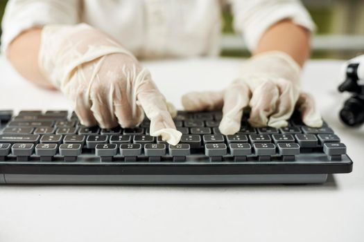 Close up shot of hands of a young child in protective gloves typing on pc keyboard