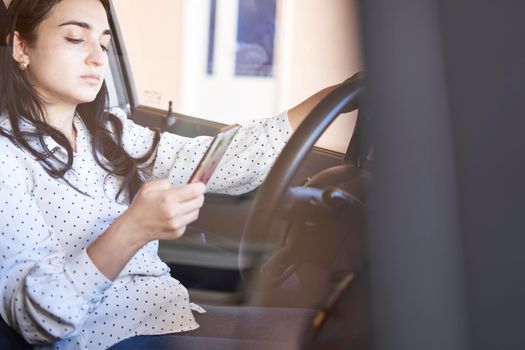 Young multiracial woman texting and driving car. Woman using cellphone while driving car. Female using smartphone while travelling by car. Driving while holding cell phone