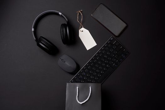 Black friday concept. A shopping bag with computer keyboard, mouse, headphones and mobile phone