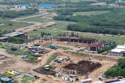 Aerial drone image (top view) of a construction site. Heavy equipment is grading the land, moving and flattening out red clay soil.