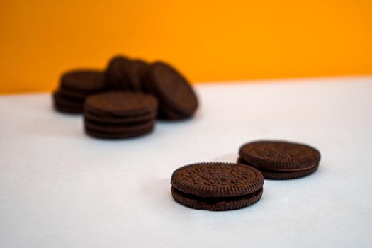 Chocolate cookies kept in a pattern on a white paper with a yellow background