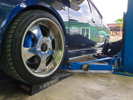 Bangkok, Thailand - August 7, 2021 : Unidentified car mechanic or serviceman disassembly and checking a disc brake and asbestos brake pads for fix and repair problem at car garage or repair shop