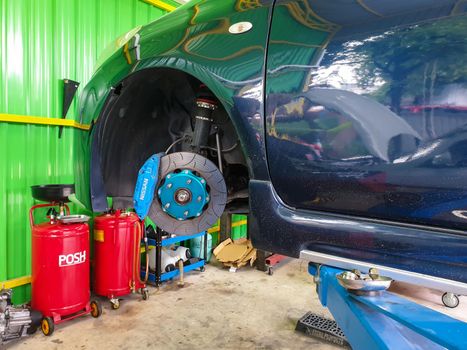 Bangkok, Thailand - August 7, 2021 : Unidentified car mechanic or serviceman disassembly and checking a disc brake and asbestos brake pads for fix and repair problem at car garage or repair shop