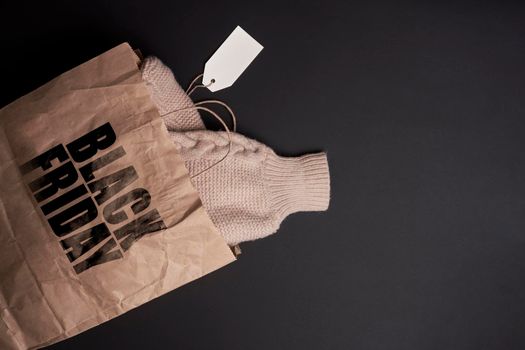 Black Friday concept. A warm knitted sweater in the shopping bag. Winter clothes purchased in Black Friday