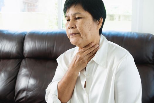 Senior adult women touching the neck feeling unwell coughing with sore throat pain.Healthcare and medicine concept