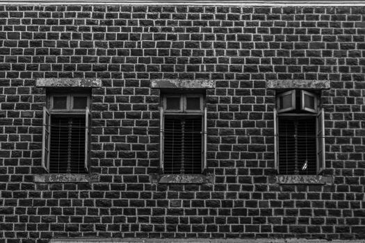 3 Vintage windows in wooden frame on a grunge damaged wall forming a pattern, in black and white