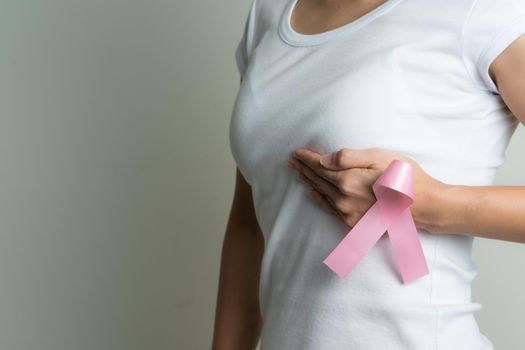 Woman hand holding pink ribbon breast cancer awareness.