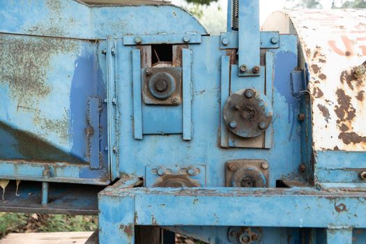 Old rusted machinery painted in blue color kept under sunglight.
