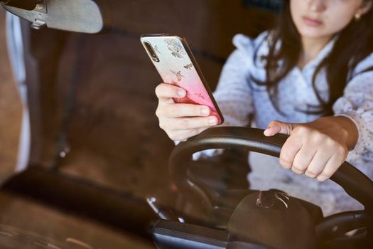 Young multiracial woman texting and driving car. Woman using cellphone while driving car. Female using smartphone while travelling by car. Driving while holding cell phone