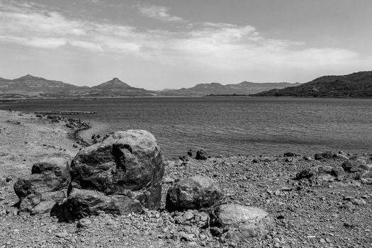 landscape of a lake from its rocky shore with mountains in the background