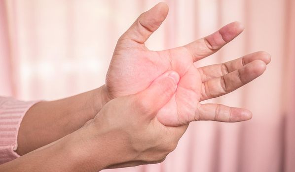 Closeup of female holding her painful palm and numbness caused by prolonged work on the computer or housewife, Carpal tunnel syndrome, arthritis. Neurological disease concept.