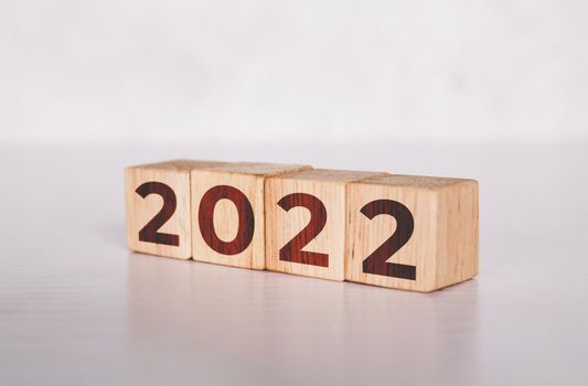 Cube wooden block with text year 2022, beginning and trend, calendar and time, determination target and planning for achievement, motivation and aspirations and improvement, business concepts.