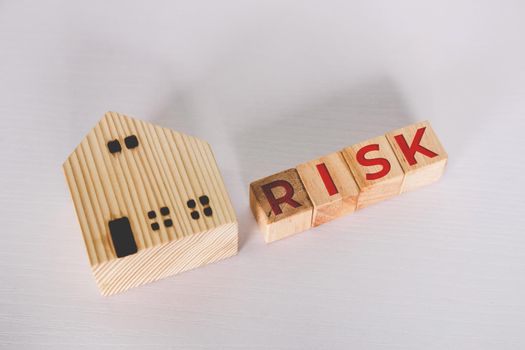 Planning with finance and investment for strategy of business about real estate with risk, uncertainty for economy, cube wooden block with word RISK and home, safety and insurance, business concepts.