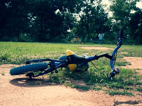 Balance bike lying on the grass in the summer park. Falling off a bike on a sunny day.