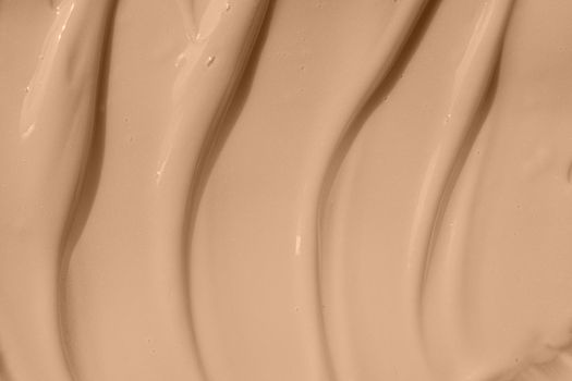 Beige nude liquid foundation smear, concealer texture smudge. Make up base drops, cream textured background. Closeup macro. Cosmetic tonal makeup moisturizer, bb cream swatch sample.