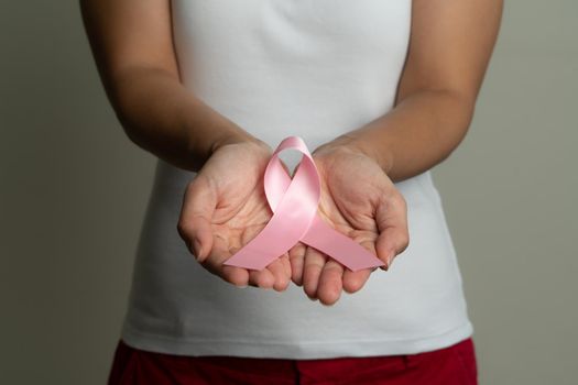 Woman hand holding pink ribbon breast cancer awareness.