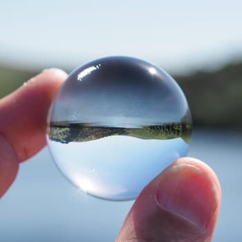 Meldon Reservoir and background hills of Corn Ridge and Black Tor captured in a crystal glass lens ball, Dartmoor National Park, Devon, UK