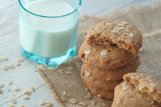 stack of whole meal cookies and glass of milk on table .