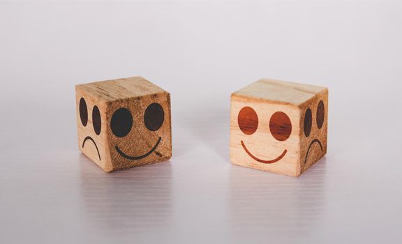 Facial on cube wooden block with emotion and expression about sincerity and frankness with metaphor on desk, symbol of positive with smile and happy concepts, negative or sham with unhappy.