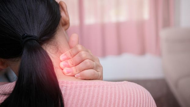 Close up of female massaging her painful neck caused by prolonged work on the computer or phone. Neck, trapezoid and shoulders pain. Muscle spasm.