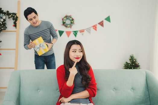 Christmas Asian Couple. A handsome man giving her girlfriend/wife a gift at home celebrating New Year People