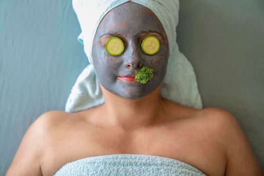 Young woman with cosmetic mask and natural vegetables on face. Concept of natural cosmetics