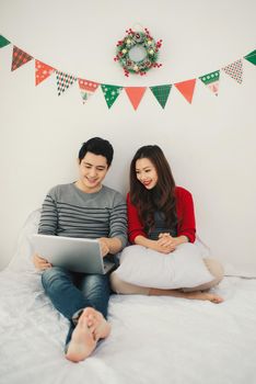 Christmas. Asian Couple using digital tablet at home celebrating New Year.