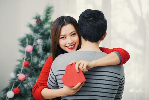 Christmas Asian Couple. A handsome man giving her girlfriend/wife a gift at home celebrating New Year People