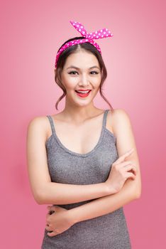 Portrait of beautiful pinup asian woman with vintage makeup and hairstyle. Isolated on pink background