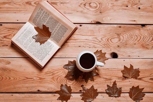 Reading a book in a cozy autumn day. Cold autumn morning with cup of coffee and book. Fall autumn weekend, leisure, mental day off, relaxing at home