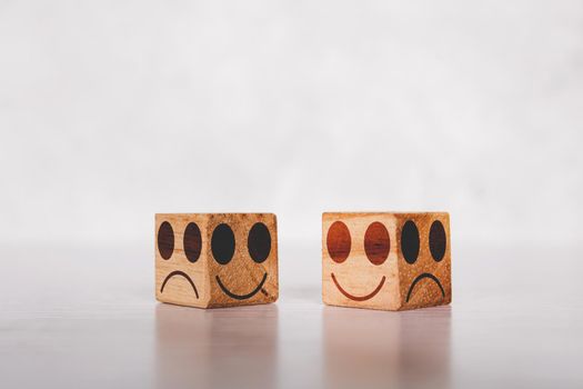 Facial on cube wooden block with emotion and expression about sincerity and frankness with metaphor on desk, symbol of positive with smile and happy concepts, negative or sham with unhappy.