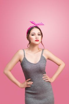 Portrait of beautiful pinup asian woman with vintage makeup and hairstyle. Isolated on pink background