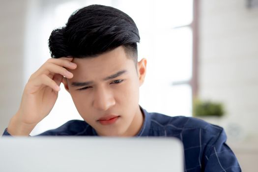 Young asian business man headache during working on laptop computer with deadline on desk at home, businessman with failure exhausted and tired, stress and worried, frustrated and unsuccessful.