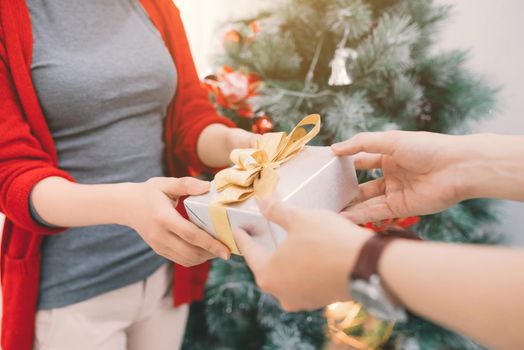 Christmas Asian Couple. A handsome man giving her girlfriend/wife a gift at home celebrating New Year People