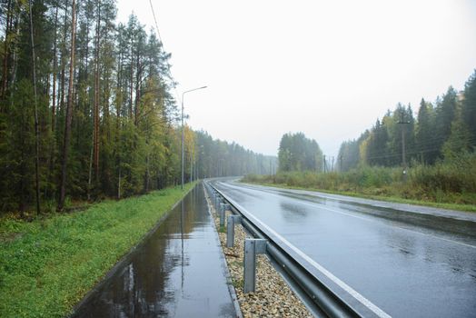 A road section with a pedestrian path located along it by rainy weather