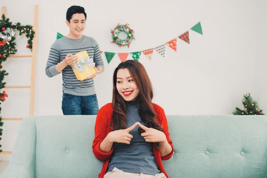 Christmas Asian Couple. A handsome man giving her girlfriend/wife a gift at home celebrating New Year People