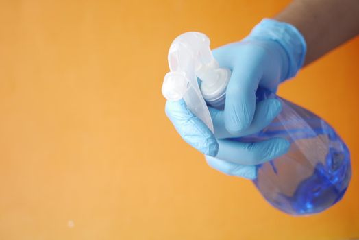 hand in blue rubber gloves holding spray bottle ,