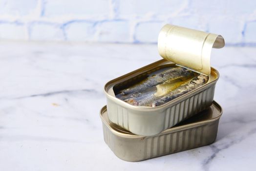 open tin of sardines on white tiles background