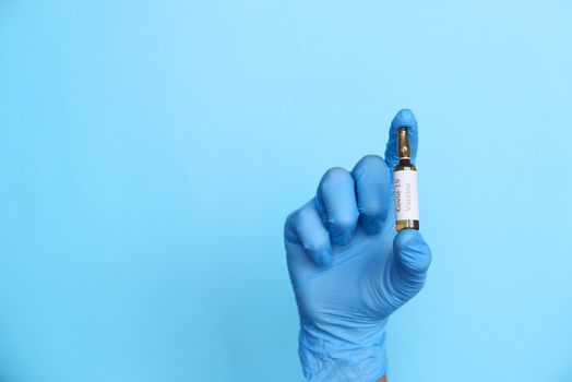 doctor hand in gloves holding coronavirus vaccine, close u.