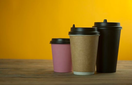 three colorful paper coffee cup on a table in a cafe, mock up
