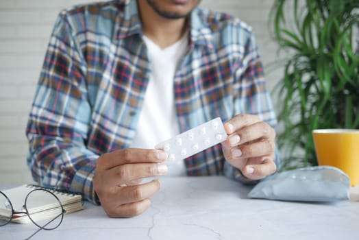 young man hand holding blister packs white sited .