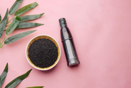 Black Cumin in a container with oil in a jar on pink