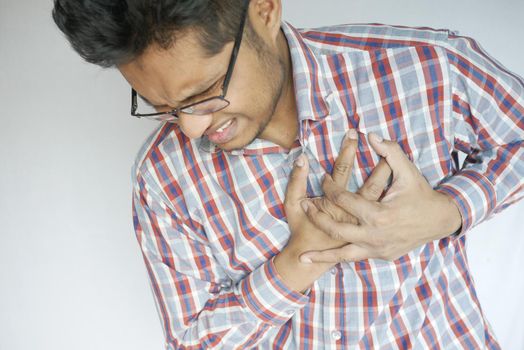 young man suffering pain in heart and holding chest with hand .