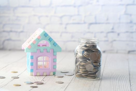 coins in a jar and house on table , the concept of house finance .