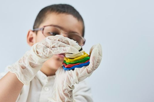 Little boy scientist in white making experiments against the white background