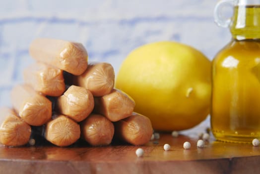 stack of sausages , lemon and oil on table ,