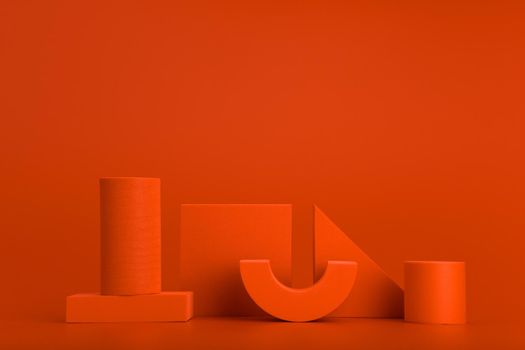 Abstract futuristic orange background. Minimal composition with different orange geometric figures in a row against orange background with copy space